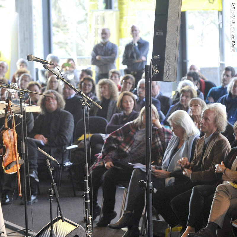 Mit einem Novum wartet der „Tag der Menschenrechte“ 2015 auf, der im Foyer des Stadttheaters begangen wird: In die Matinee, mit ihrem traditionellen Programm aus einer Rede, Musik und einer Informationsbörse, wird der Theaterfrühschoppen zu Marco Stormans Inszenierung von „Nathan der Weise“ integriert. Lessings Drama verhandelt große Menschenrechtsthemen, wie sie aktueller und brisanter nicht sein könnten: Christen, Muslime und Juden kämpfen erbittert gegeneinander. Lessing setzte damals auf Versöhnung, Vernunft und Toleranz.Als Redner konnte der Schriftsteller Gert Heidenreich gewonnen werden, als Marieluise-Fleißer-Preisträger in Ingolstadt bestens bekannt. Als Titel hat er gewählt: „LESSING ADIEU – Vernunft in fanatischer Zeit.“Für die musikalische Gestaltung sorgt die multikulturell besetzte Band „Radio Rumeli“,  mit  fünf Musikern aus Deutschland, Tschechien und der Türkei.Über 40 Vereine und Organisationen vertreten ihre Anliegen, verbunden mit Appellen für Menschen, die unter Menschenrechtverletzungen leiden -  rund um den Globus, u.a. in afrikanischen Ländern, in China, Vietnam und Taiwan, im Iran und in Mexiko, in Russland und Saudi-Arabien, in der Türkei, Syrien und im Irak.Schriftsteller Gert Heidenreich bei seiner Rede.